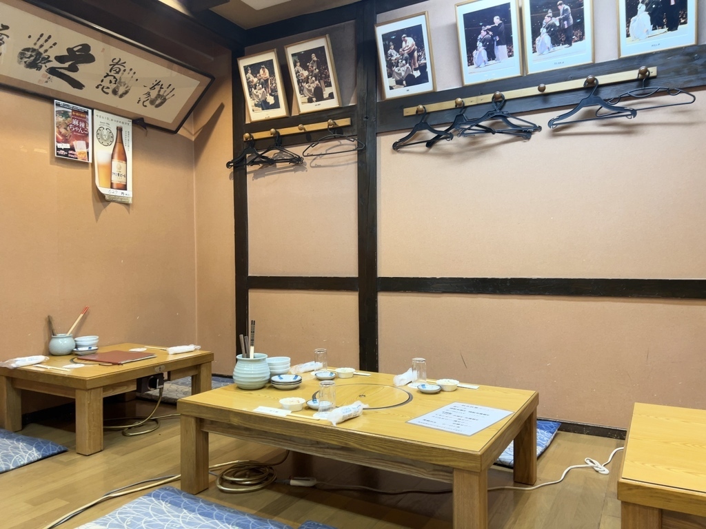 落ち着いた店内のテーブル席と相撲ゆかりの装飾